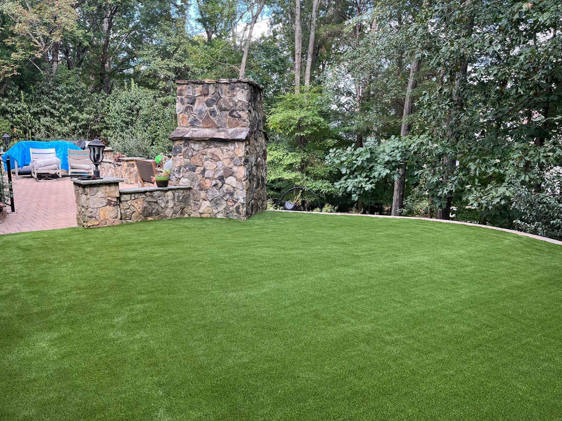 A large lawn with a stone fireplace in the backyard.