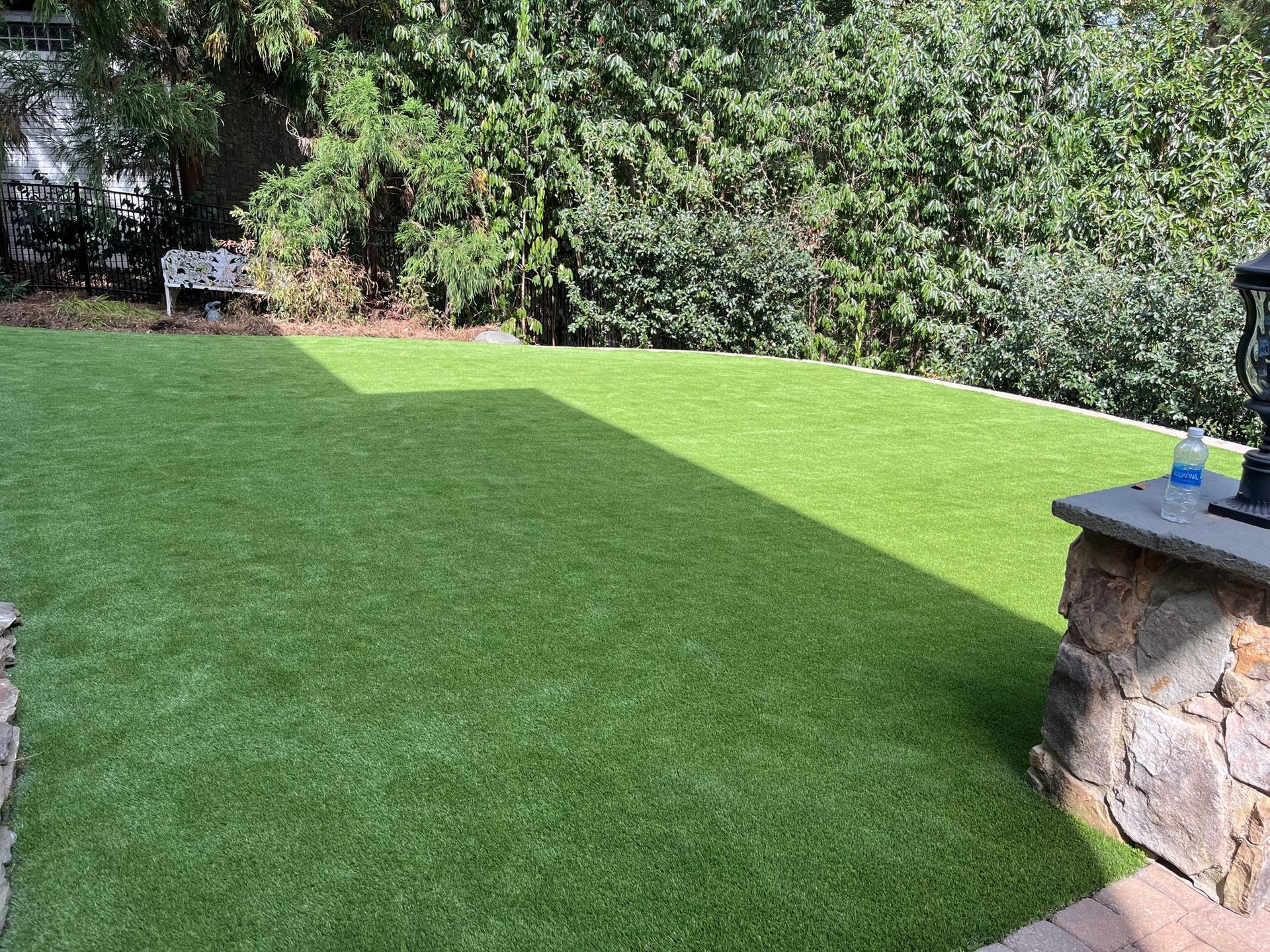 A backyard with a lush green lawn and a stone wall.