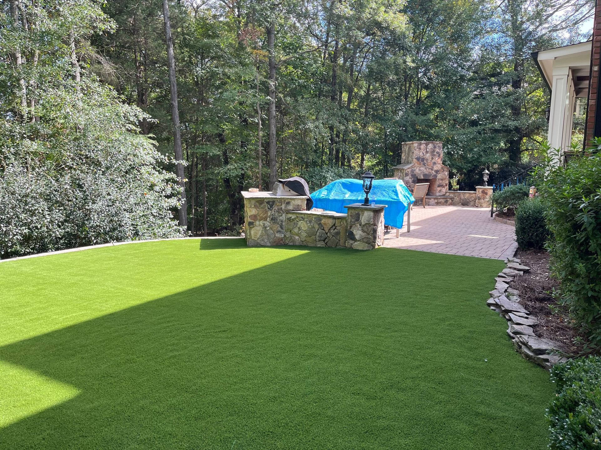 A backyard with a lush green lawn and a grill.