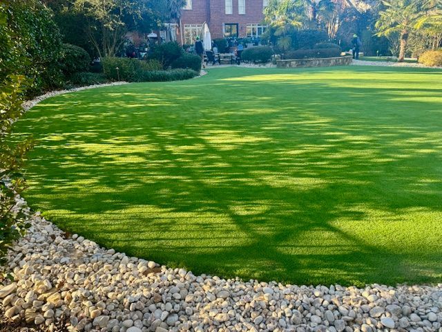 A large lawn with a lot of grass and rocks in front of a house.