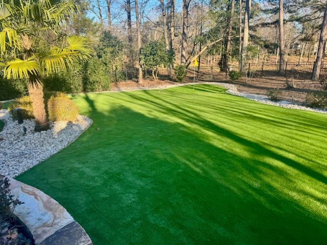 A large lush green lawn with trees in the background.