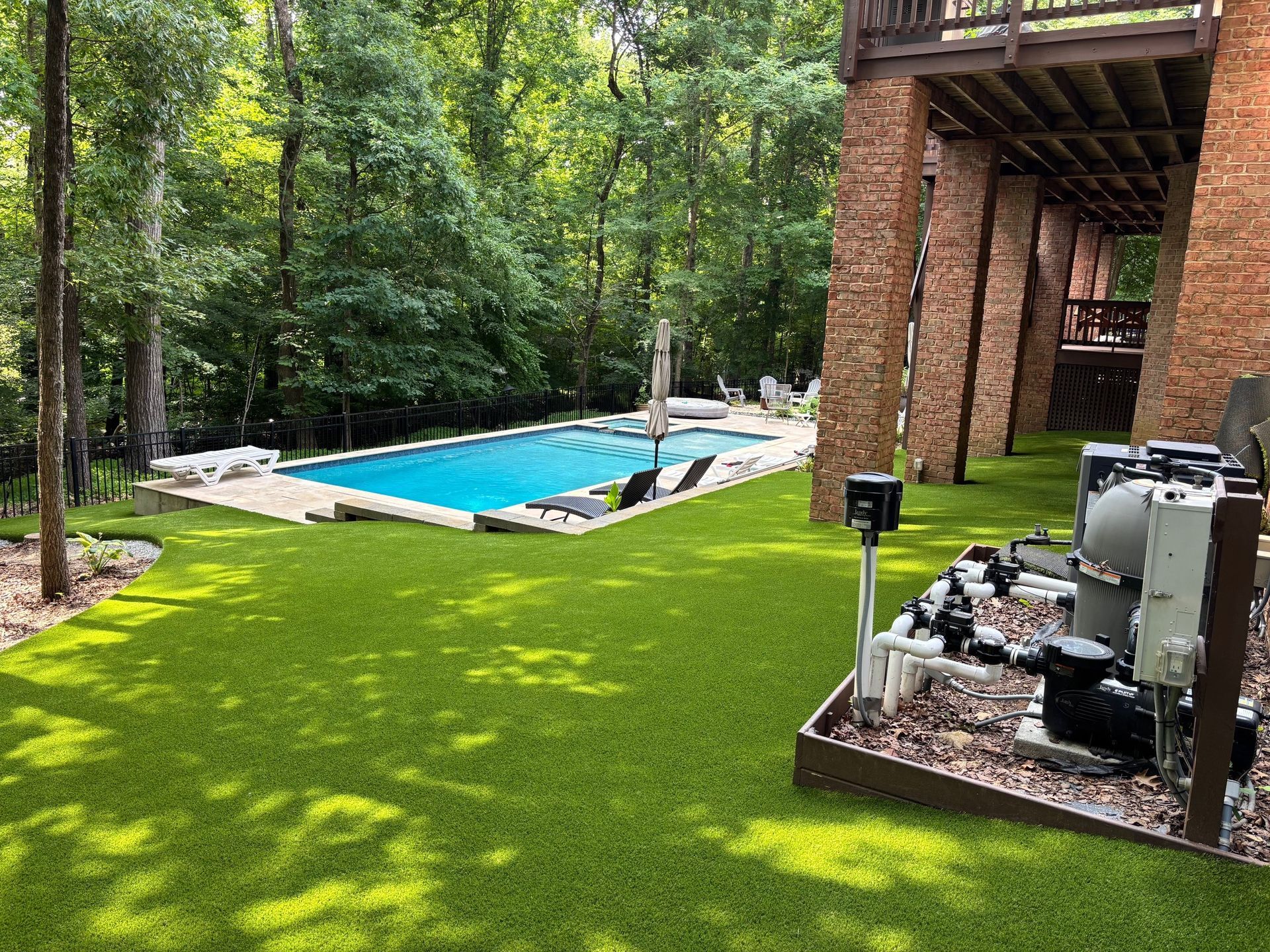 A large swimming pool is surrounded by trees in a backyard.