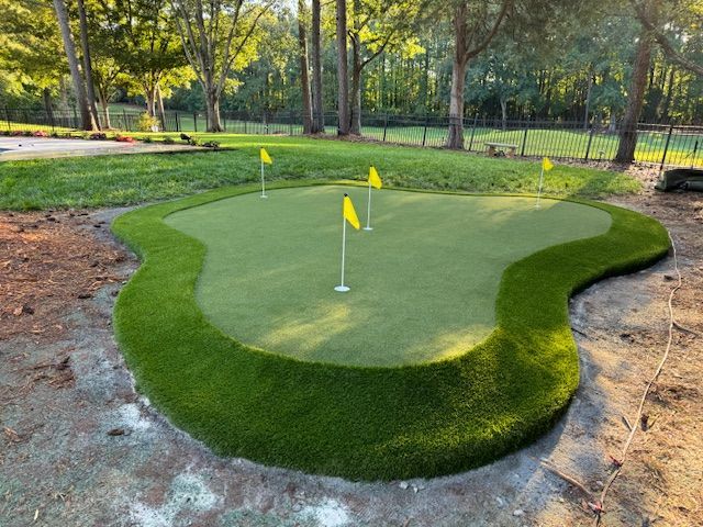 A green putting green with two yellow flags on it