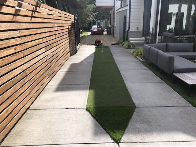 A concrete walkway with a couch and a wooden fence
