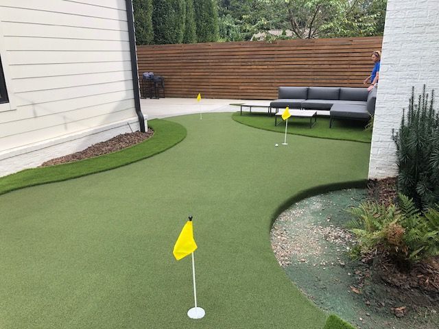 There is a putting green in the backyard of a house.