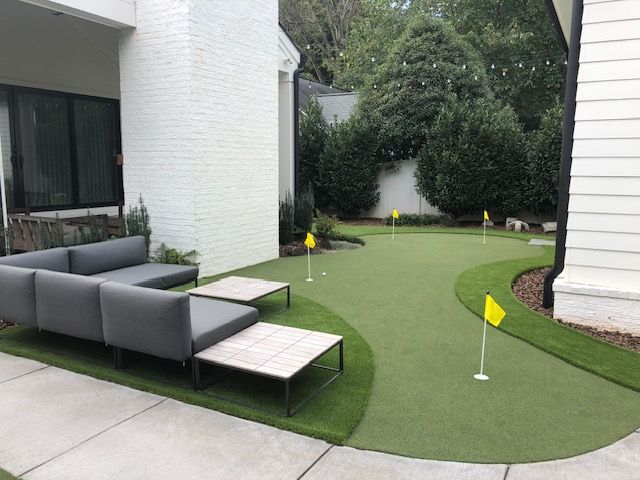 There is a putting green in the backyard of a house.