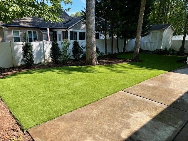 A lawn with a concrete walkway and a house in the background