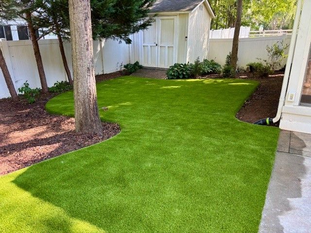 A backyard with a lot of green grass and a white shed.