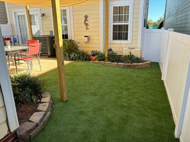 A backyard with a white fence and a table and chairs.