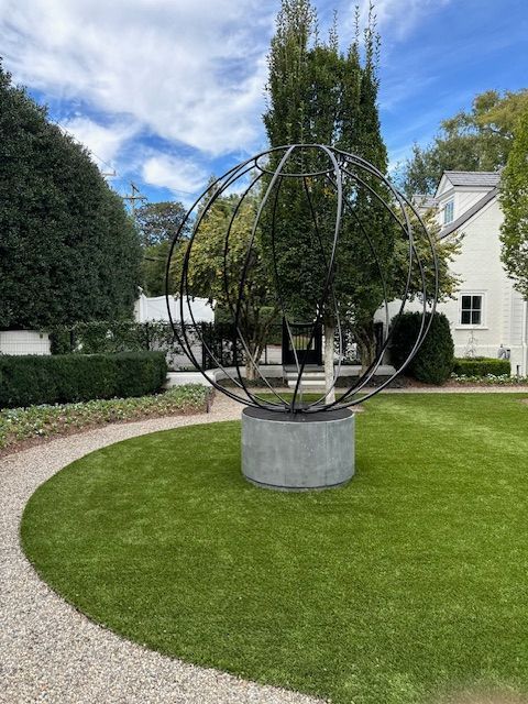 There is a large sculpture in the middle of a lush green field.