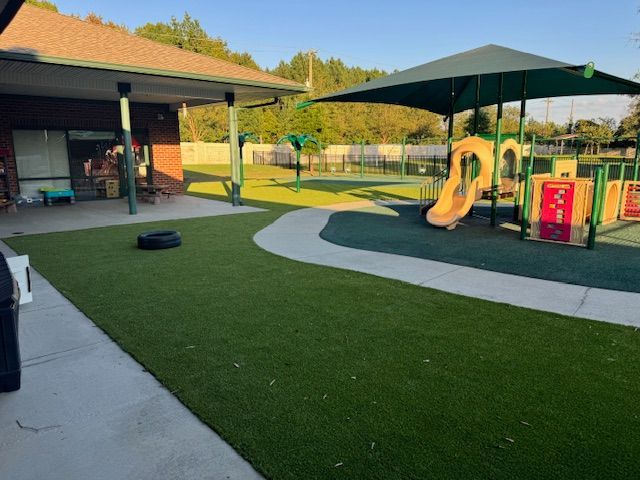 A playground with a slide and umbrellas in front of a building