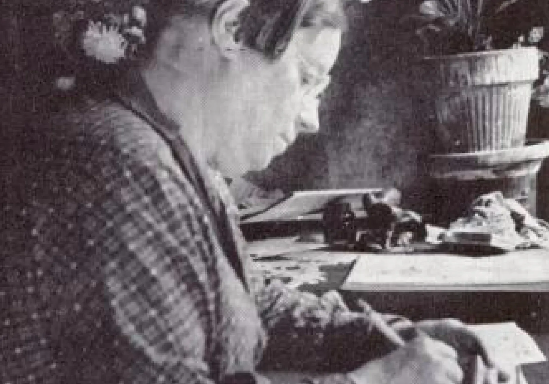 A woman is sitting at a table writing on a piece of paper.