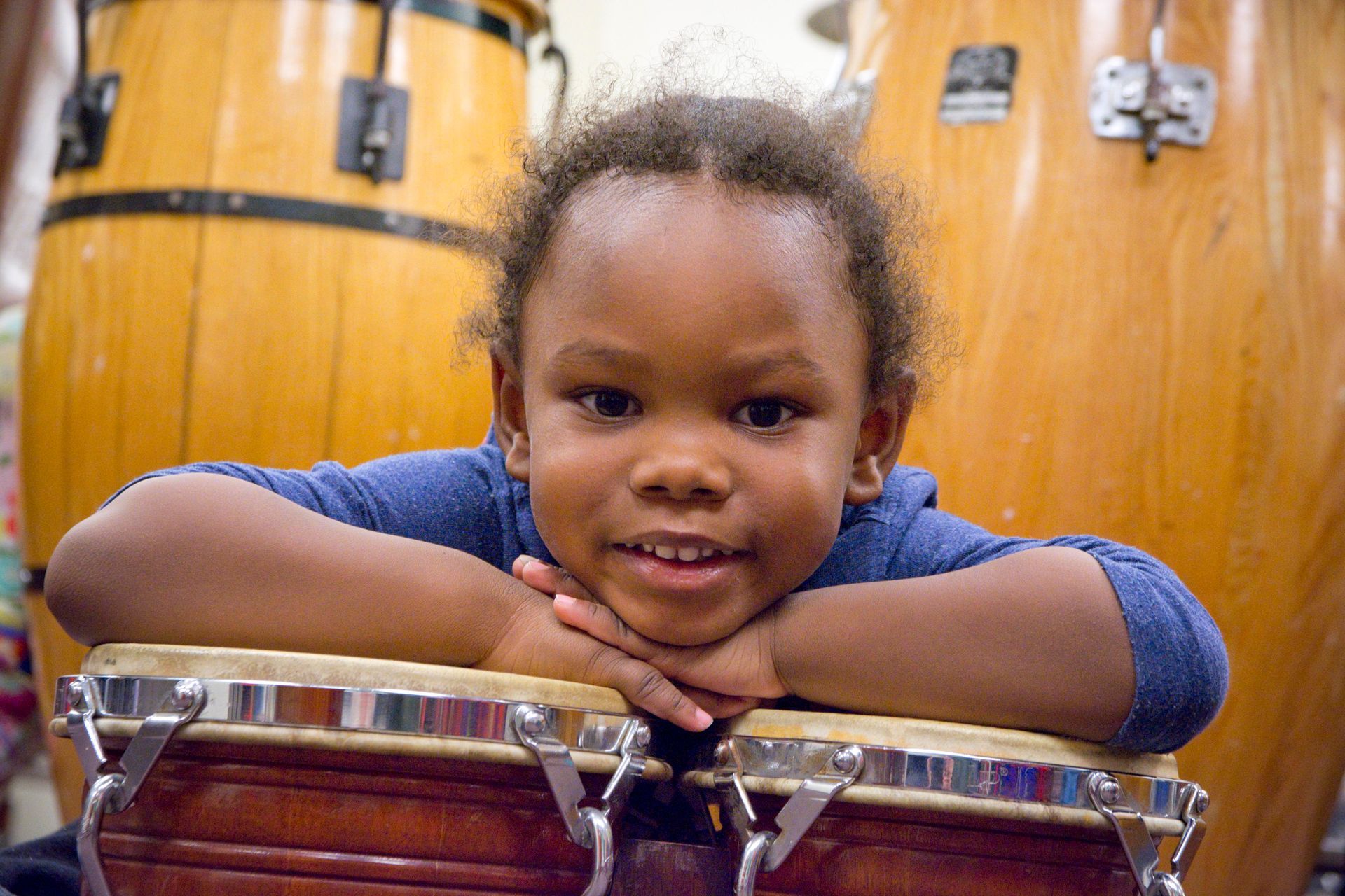 A young girl is sitting on a drum with her head resting on it.