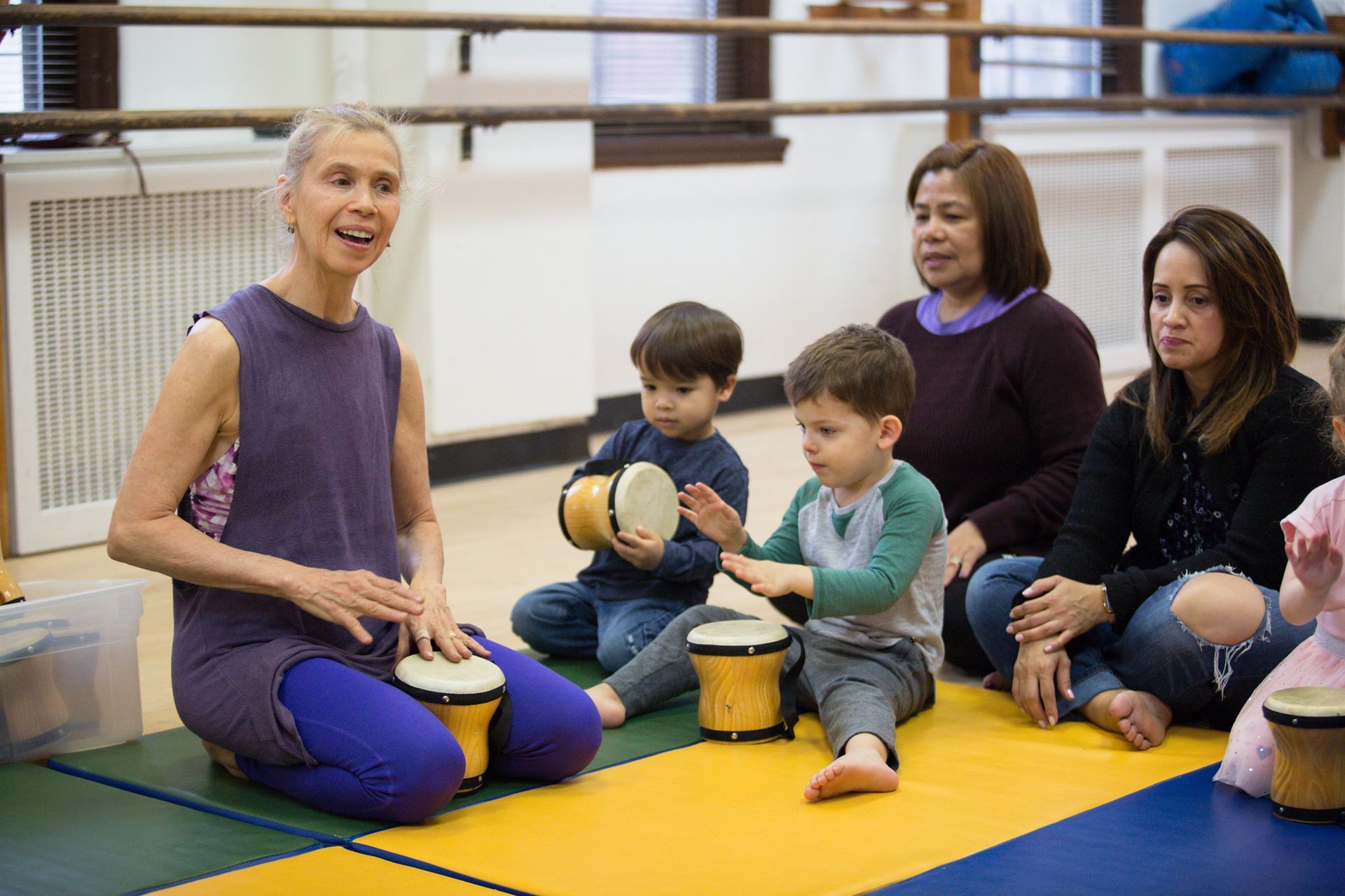 A group of people are sitting on the floor playing drums.