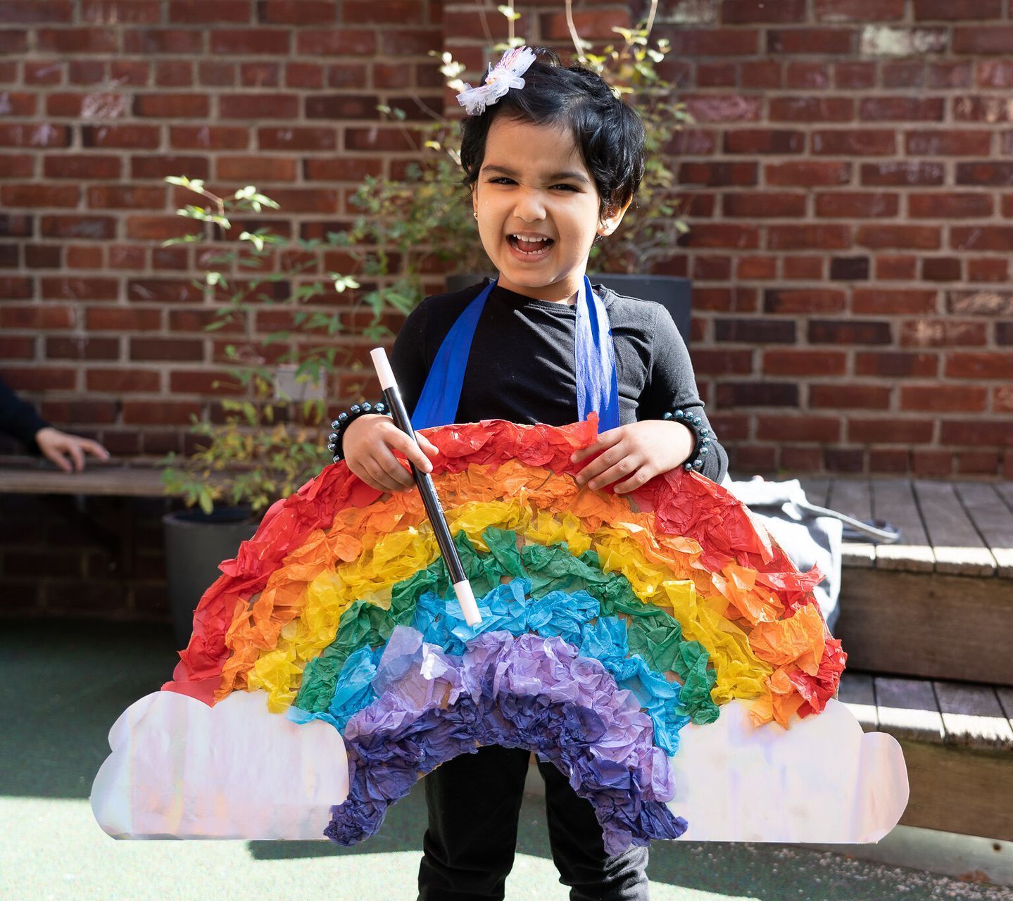 A little girl is holding a rainbow made out of paper.