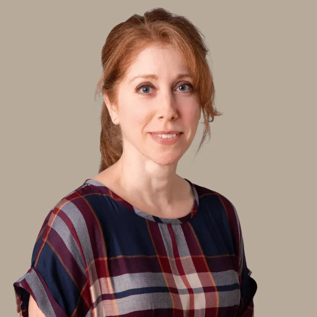 A woman in a plaid shirt is smiling for the camera.