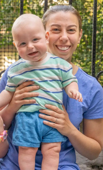 A woman is holding a baby in her lap and smiling.