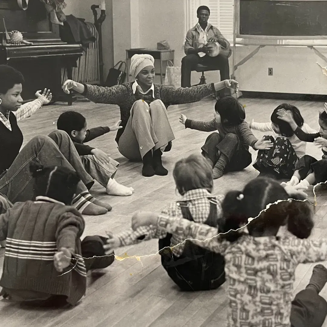 A group of children are sitting on the floor with their arms outstretched