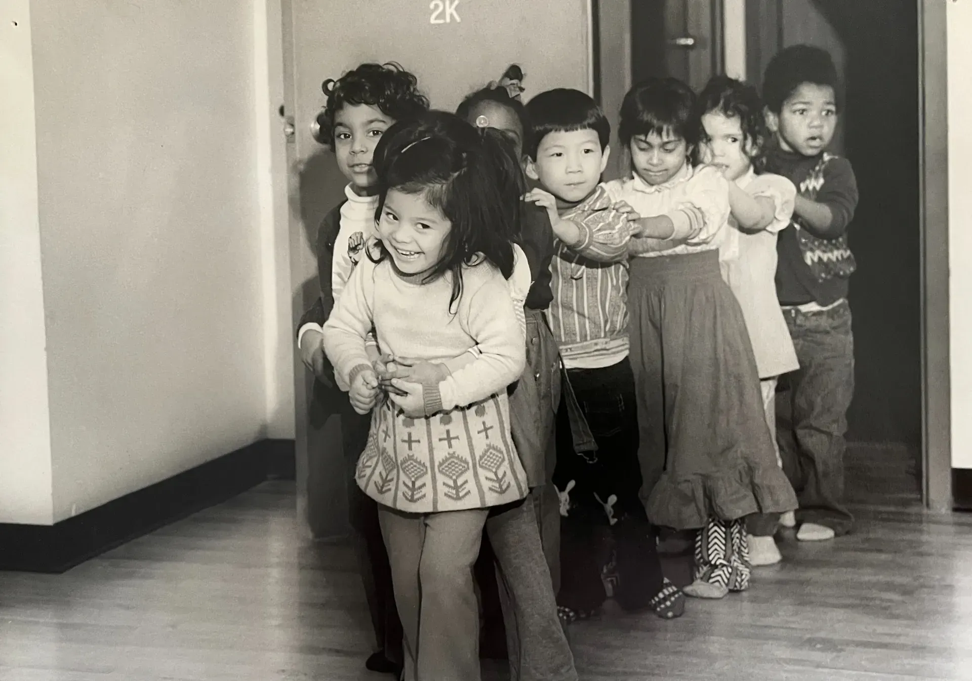A black and white photo of a group of children standing in a hallway