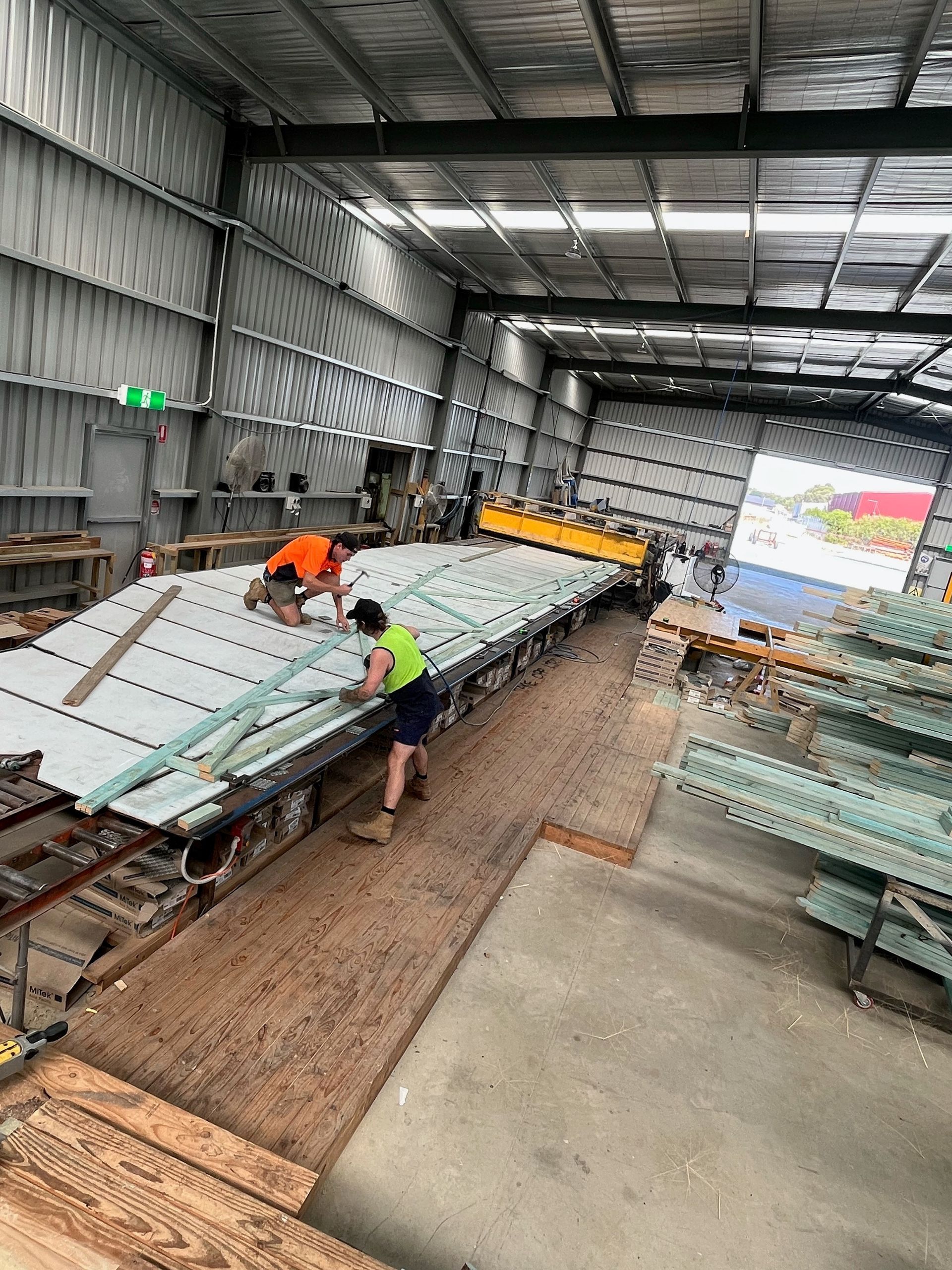 Two workers in a warehouse building a structure. 