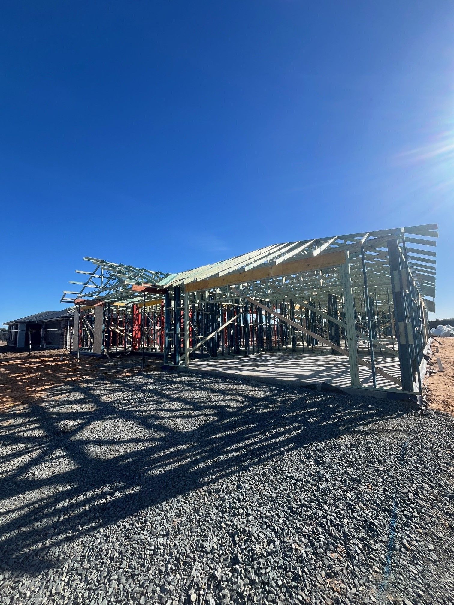 Construction site with a partially built wooden structure under a clear blue sky. 