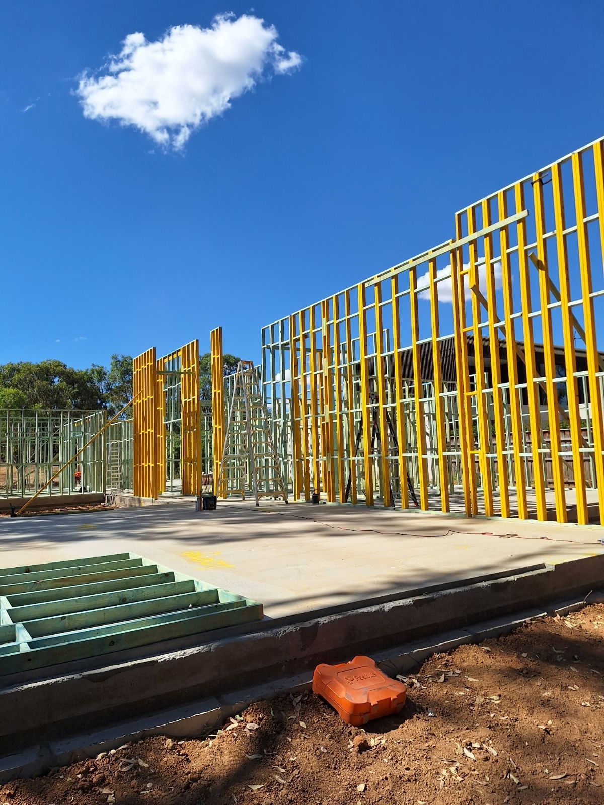 Construction site with yellow-framed walls against a blue sky with a single cloud. B