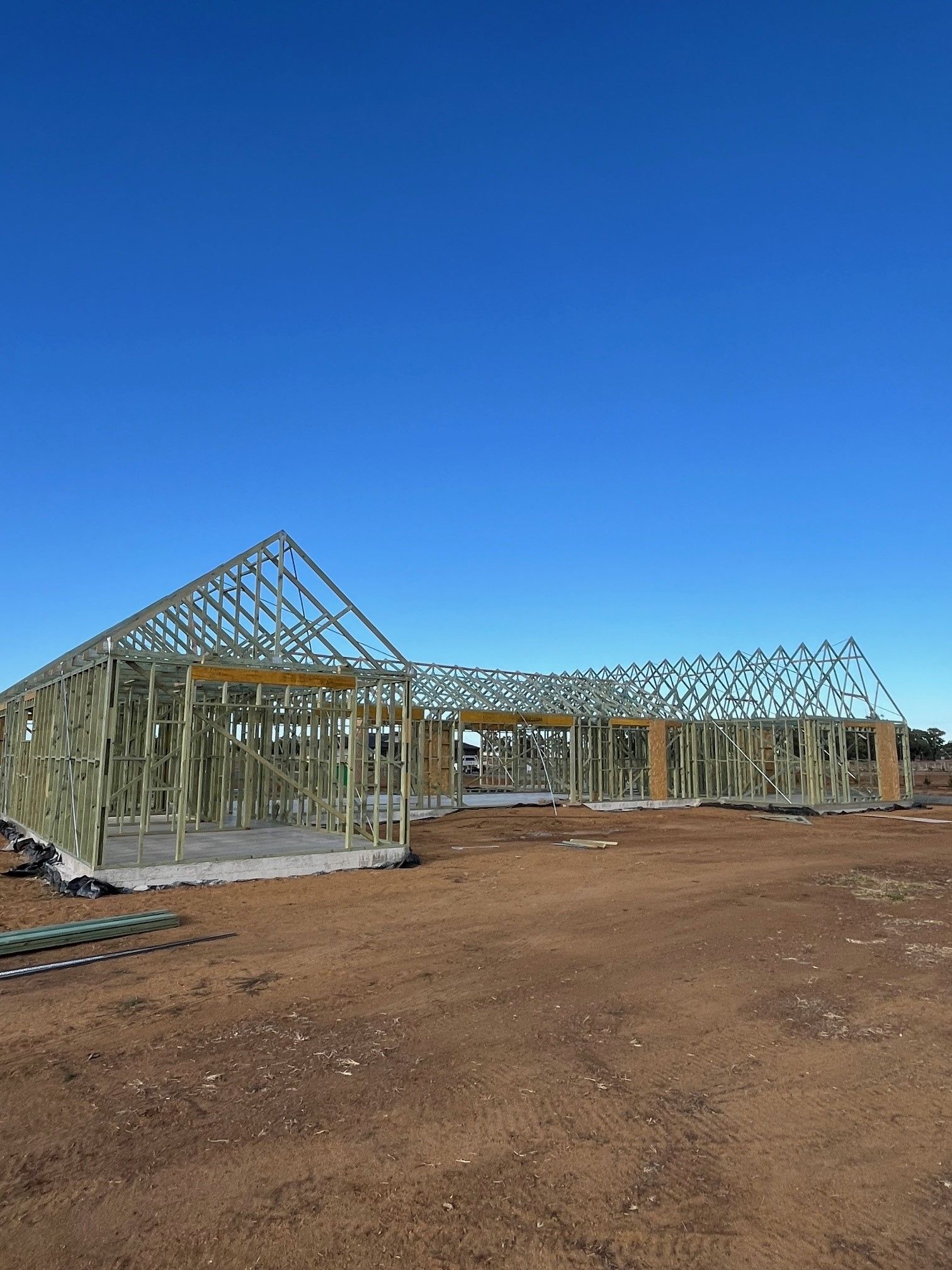 Wooden frame of a building under construction against a clear blue sky. 