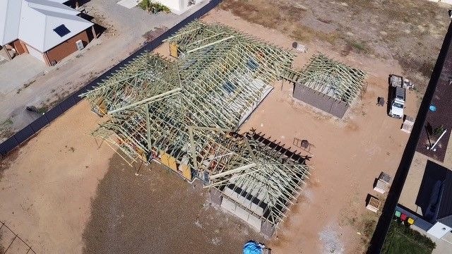 Aerial view of a residential construction site with wooden roof trusses in place.  