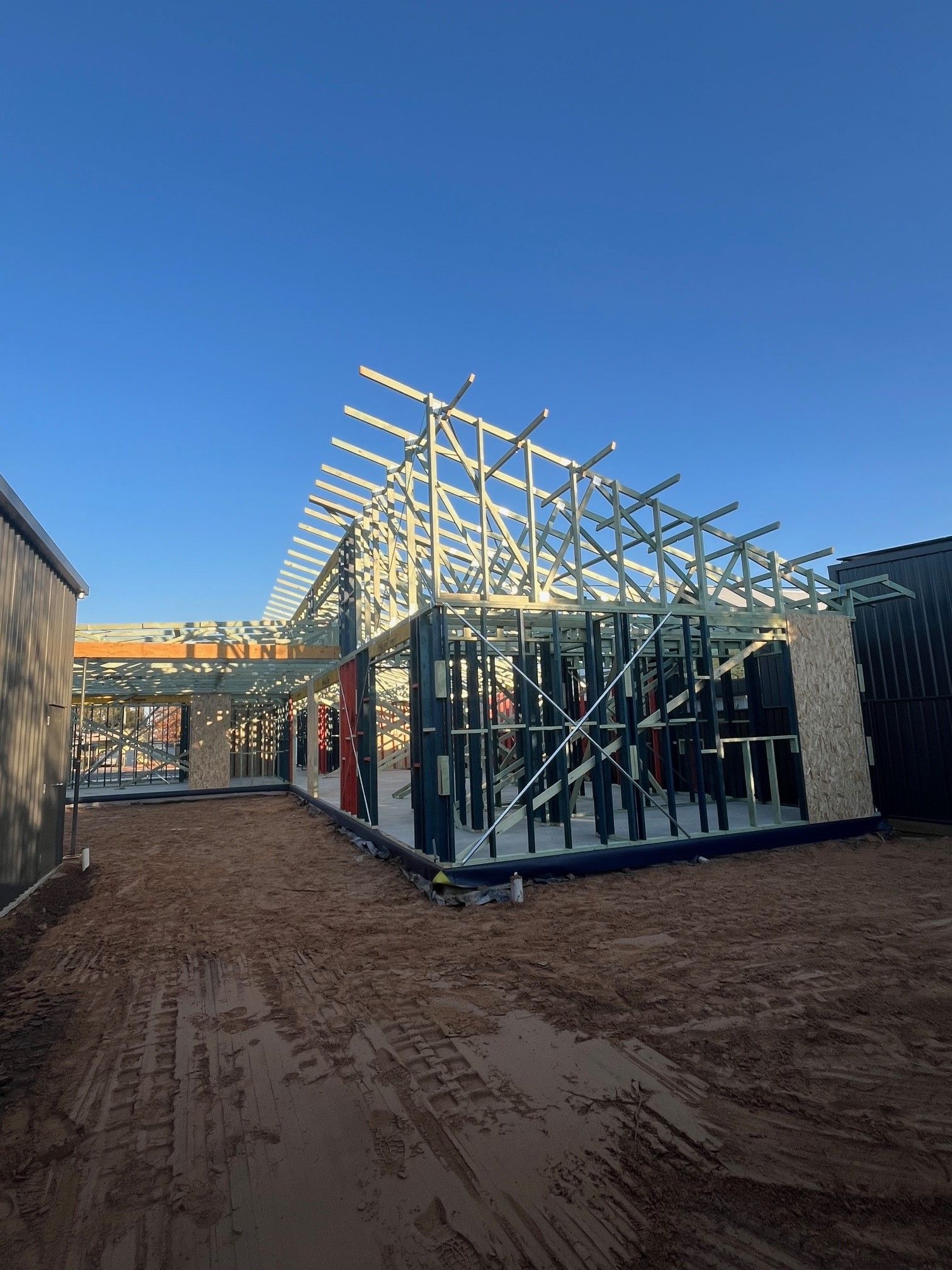 Construction site with a metal-framed building under construction against a blue sky.