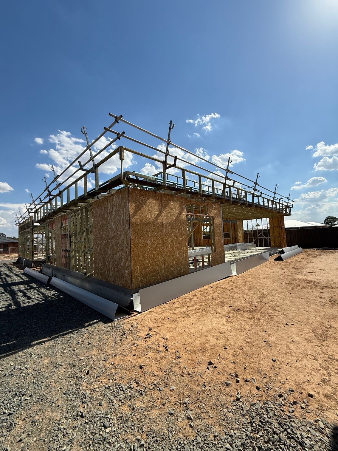 A house is being built in the middle of a dirt field.