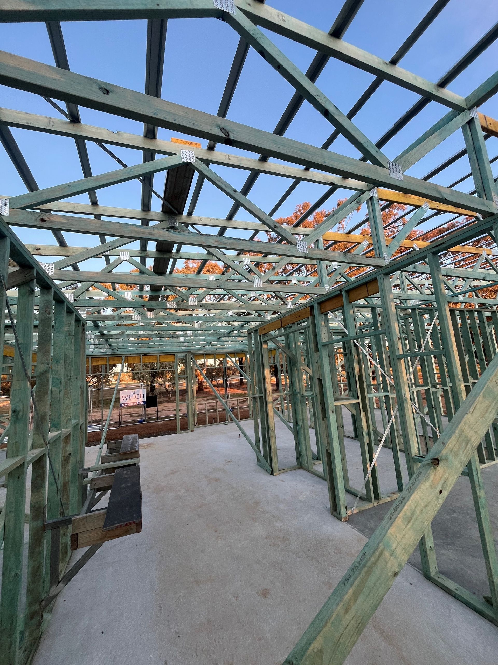 Wooden frame of a building under construction, with exposed rafters and interior walls. 