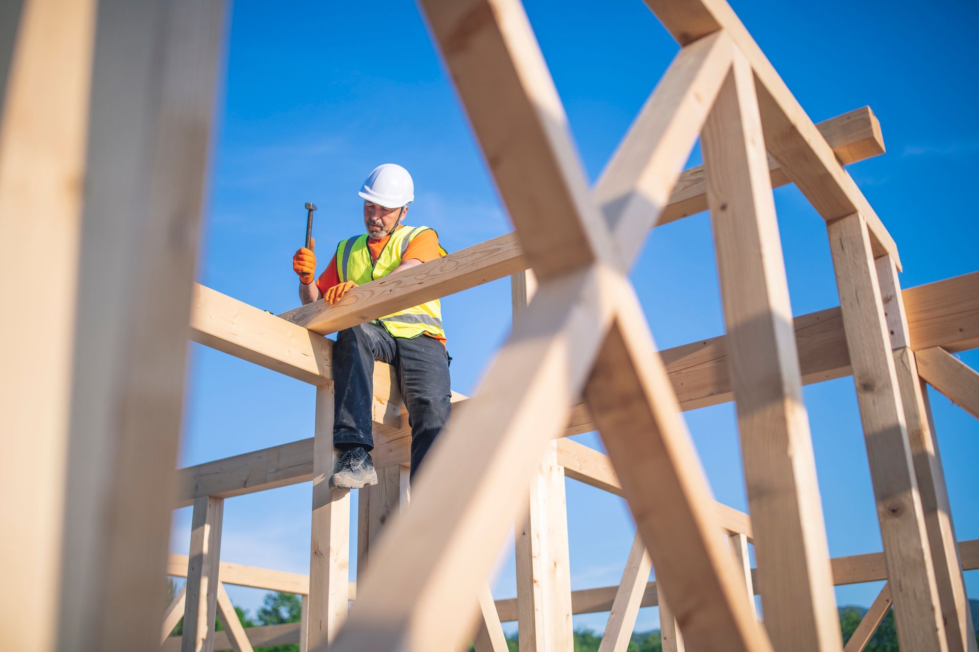 Worker measures wooden beams on building frame with tape measure. Worker measures wooden beams on building frame with tape measure.