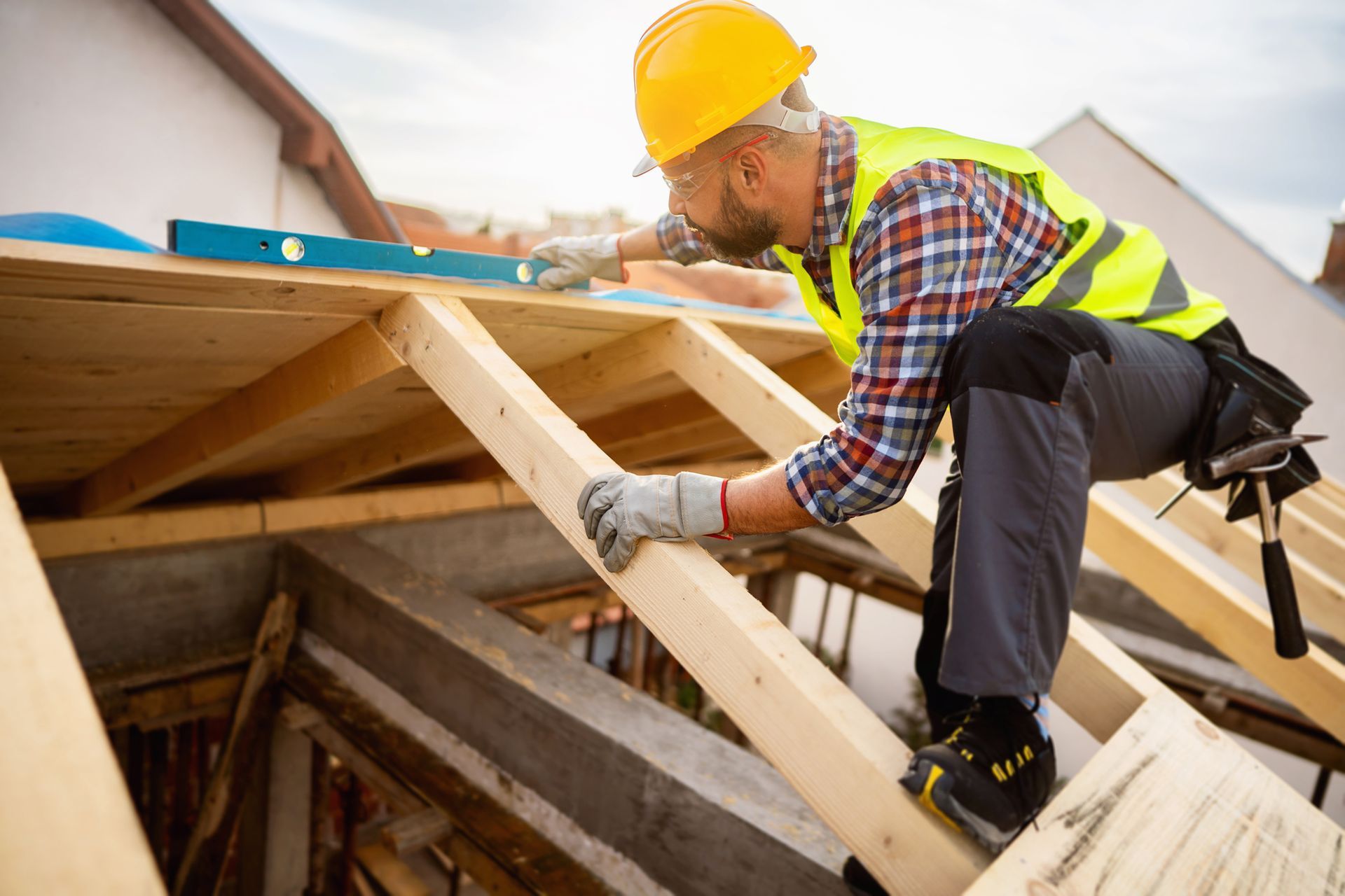 Construction worker uses level tool to measure roof frame.