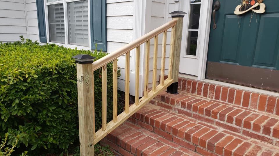 A wooden railing is attached to the steps of a brick house.