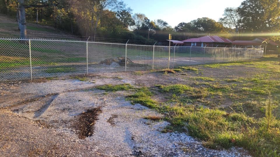 A chain link fence surrounds a dirt field.