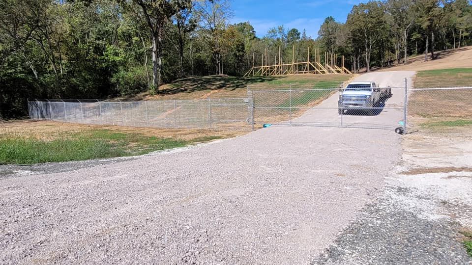 A truck is driving down a gravel road next to a fence.