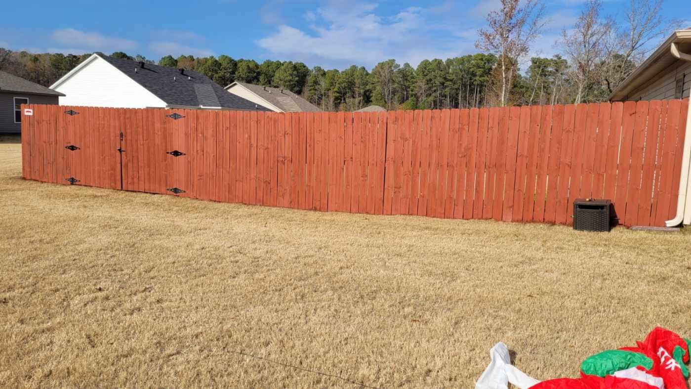 A red wooden fence is sitting in the middle of a grassy yard.