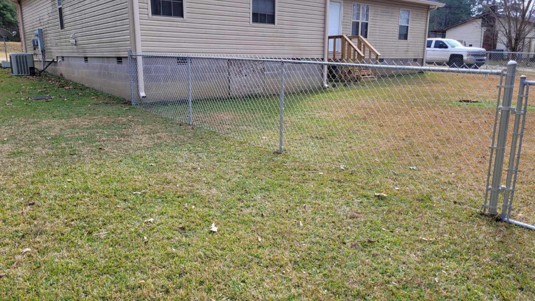 There is a chain link fence in the backyard of a house.