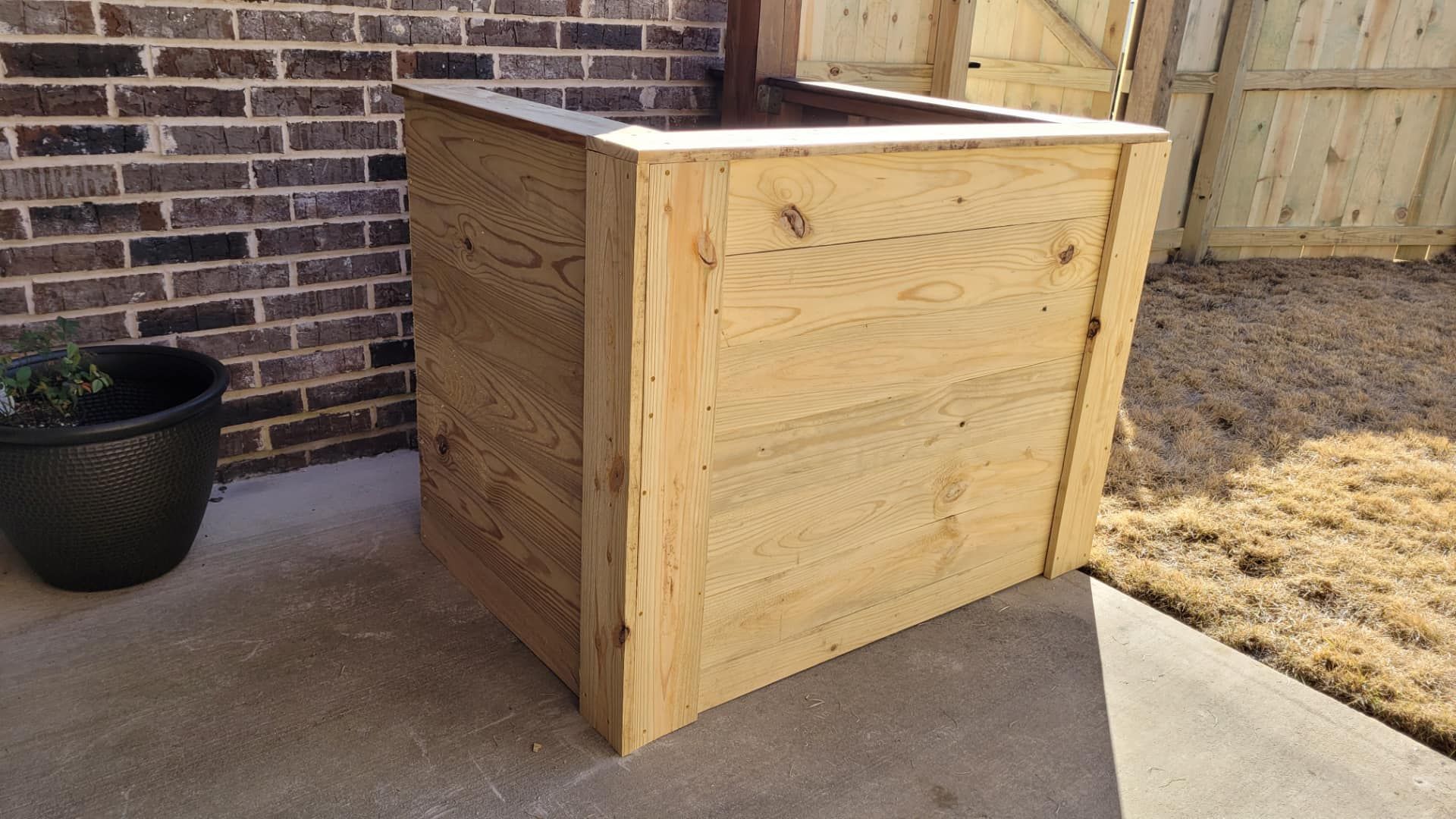 A wooden box is sitting in front of a brick wall.