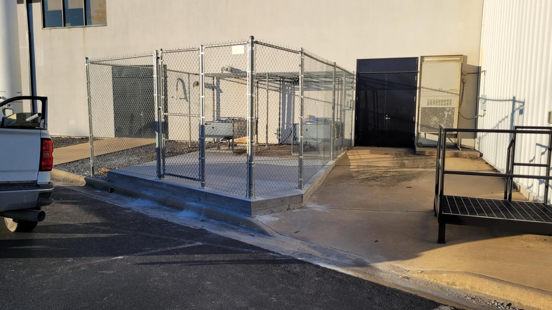 A white truck is parked in front of a chain link fence.