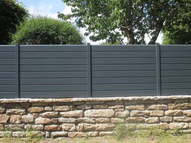 A black fence is sitting on top of a stone wall.