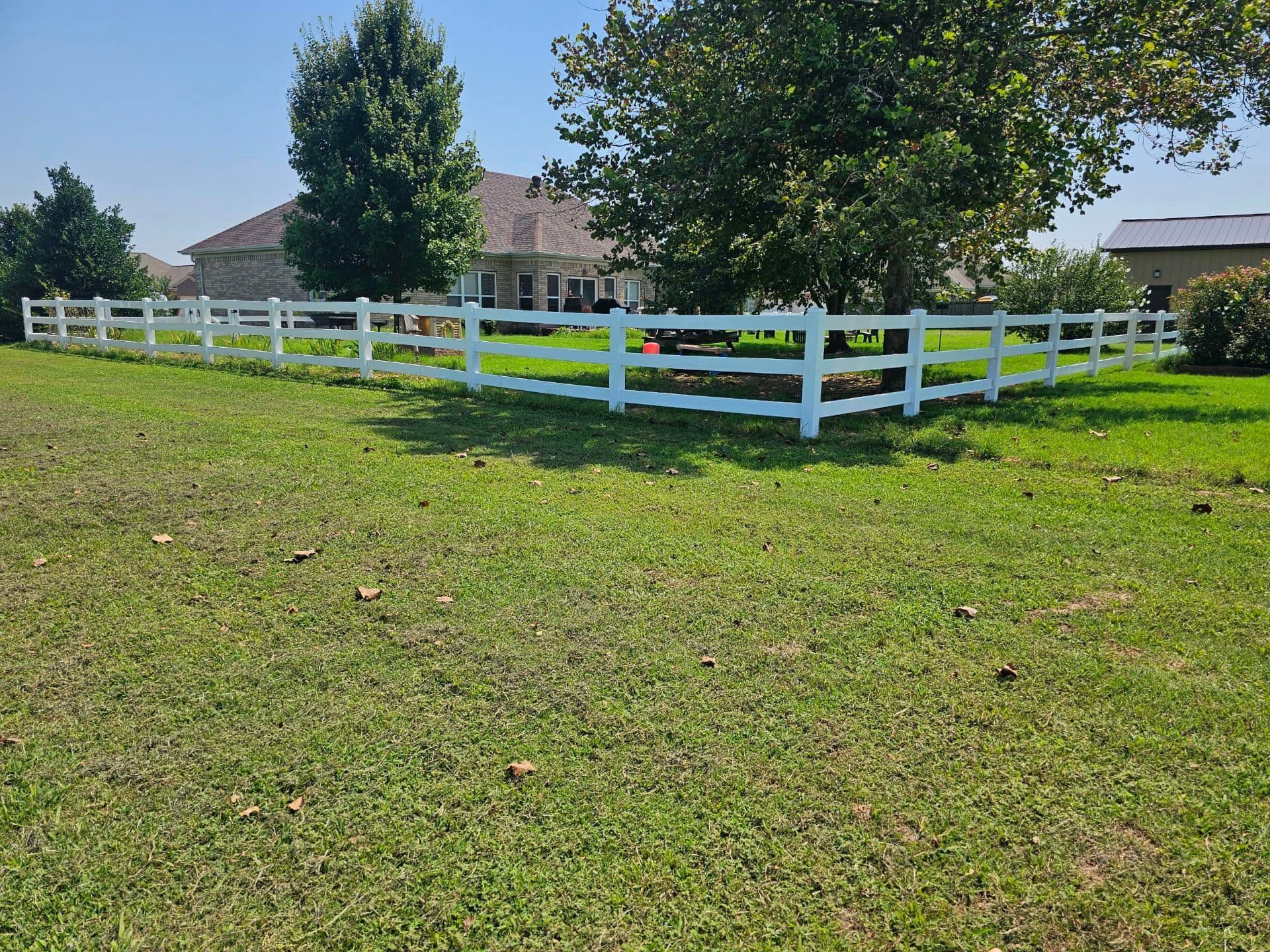 A white fence surrounds a lush green field.
