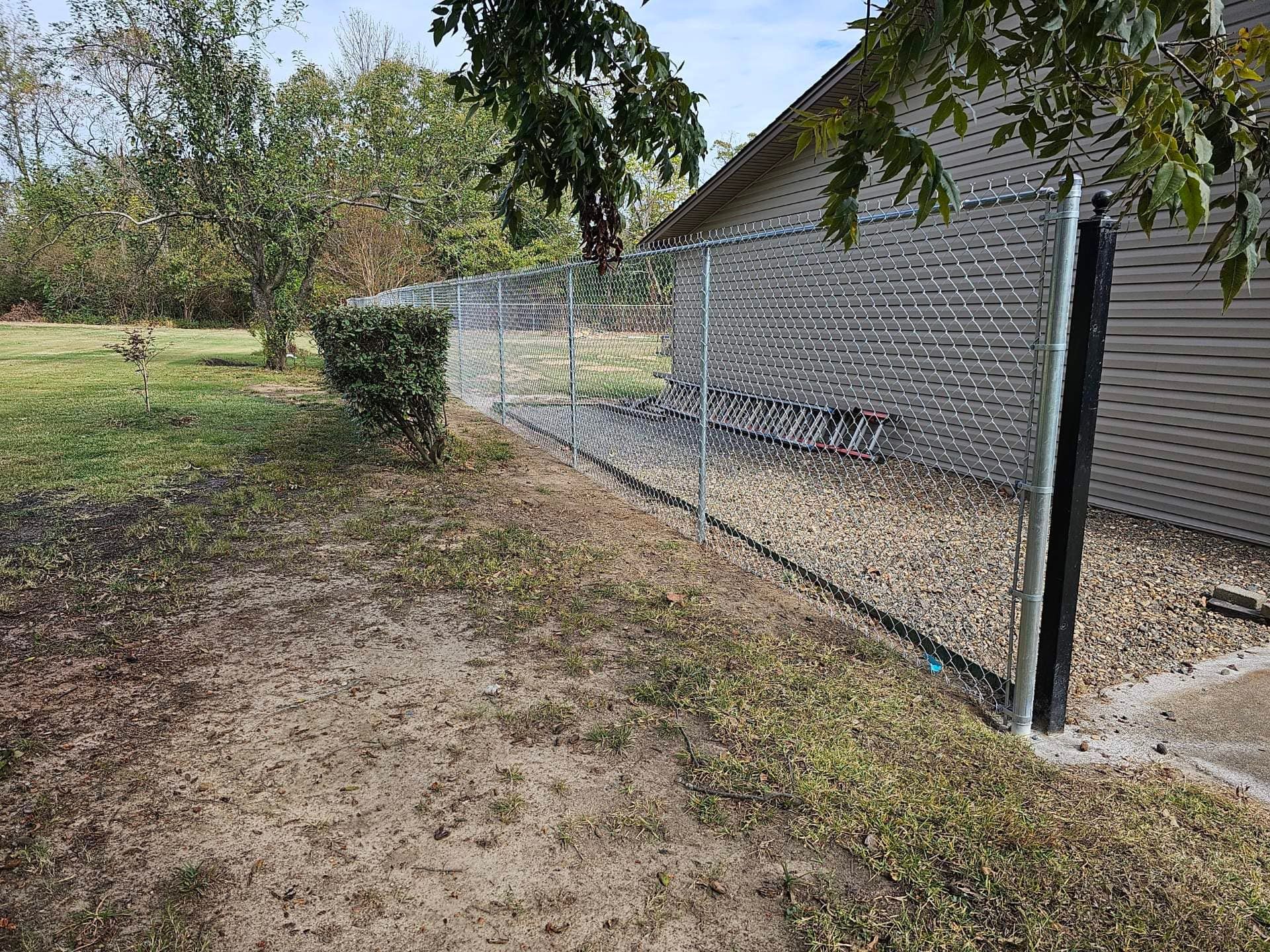 A chain link fence is surrounding a yard next to a house.