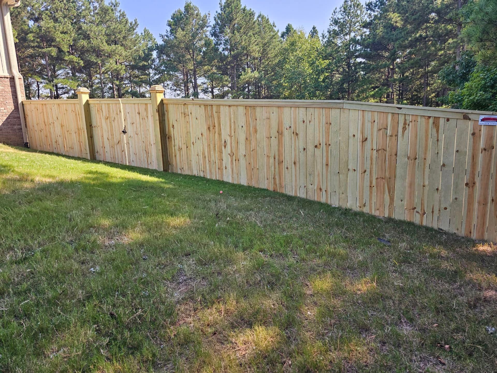 A wooden fence is in the middle of a lush green field.