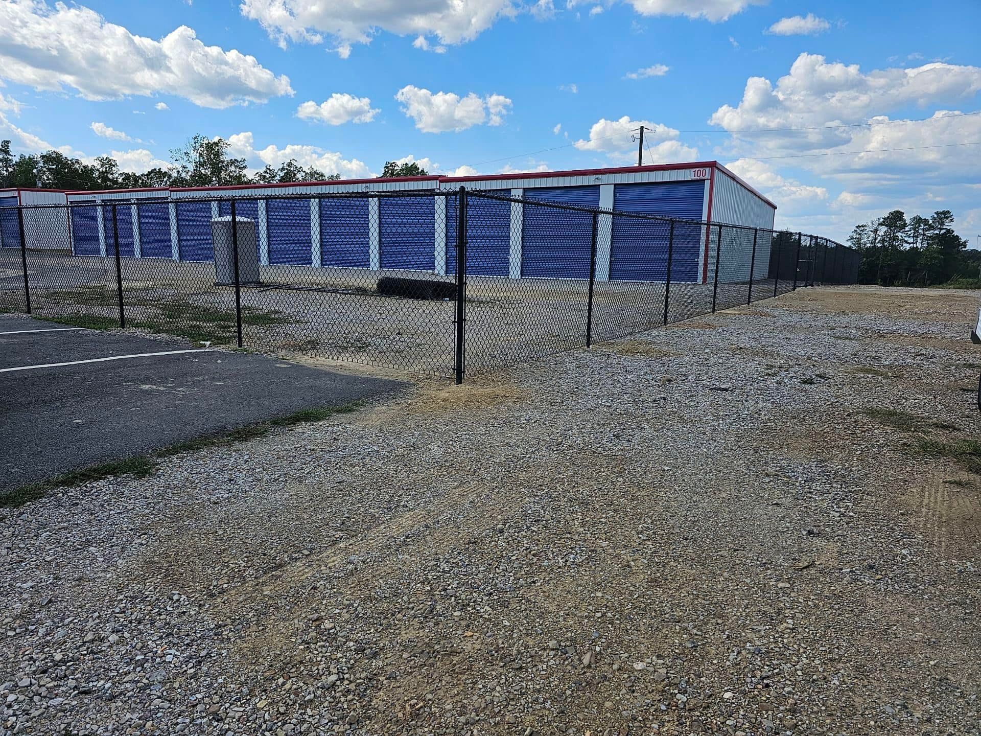 A row of storage units are behind a chain link fence.