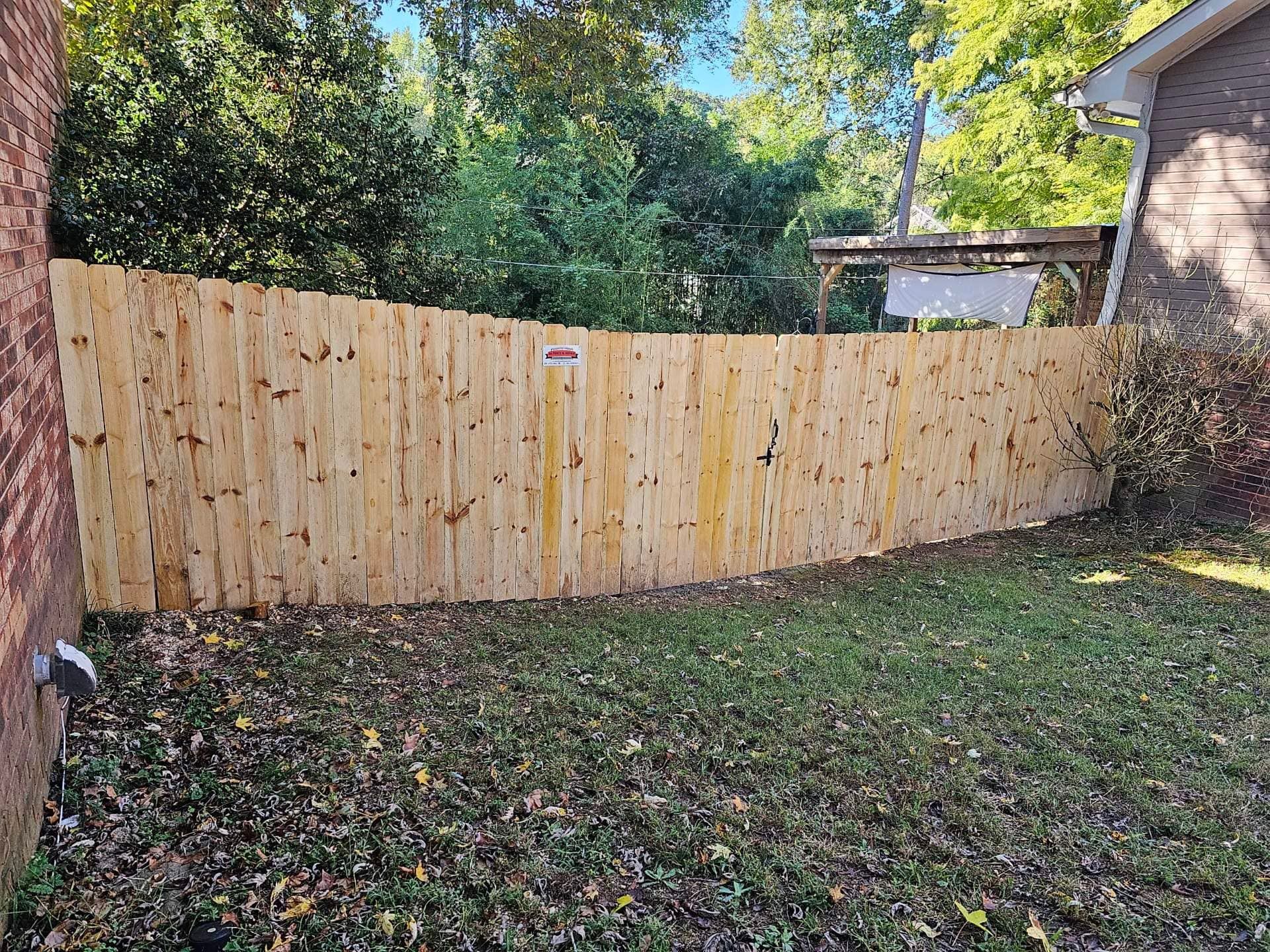 A wooden fence is in the backyard of a house.