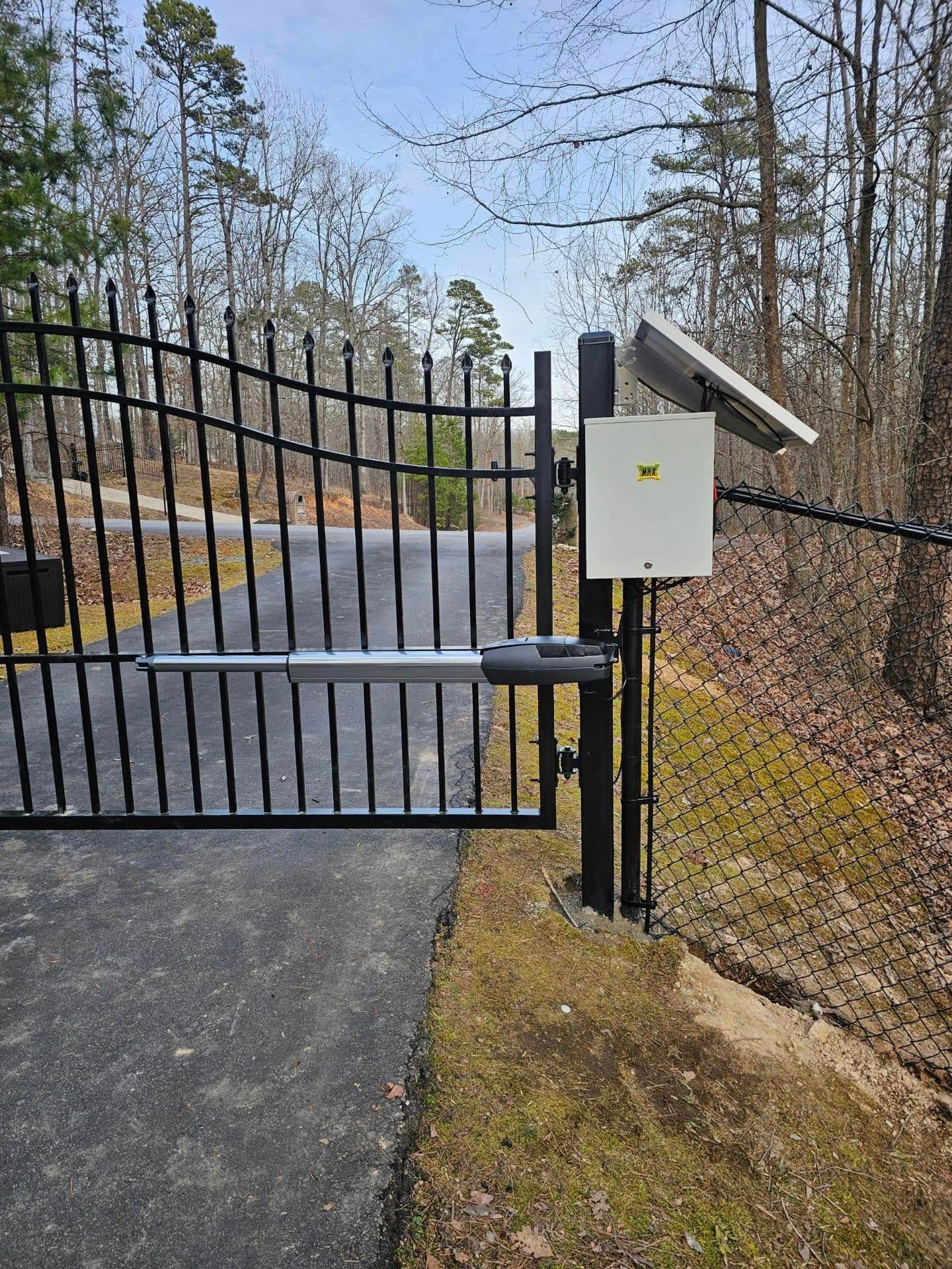 A black gate with a solar panel on top of it.