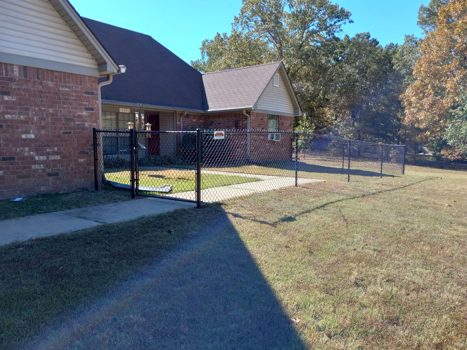 A brick house with a chain link fence in front of it.