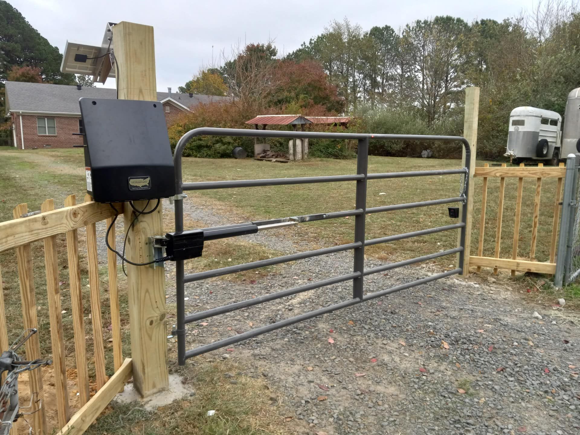 A gate with a motor attached to it is sitting next to a wooden fence.