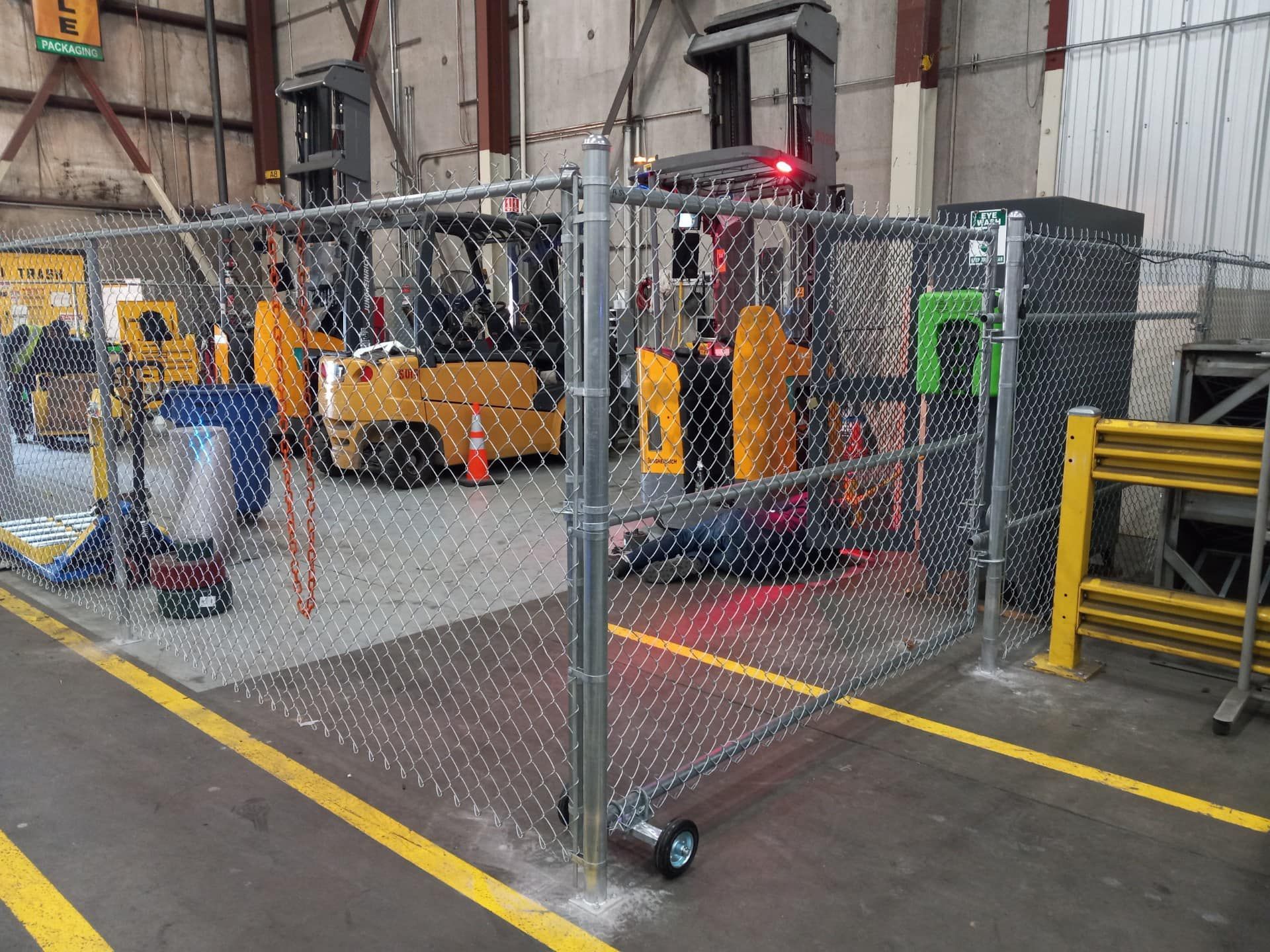 A warehouse with forklifts behind a chain link fence